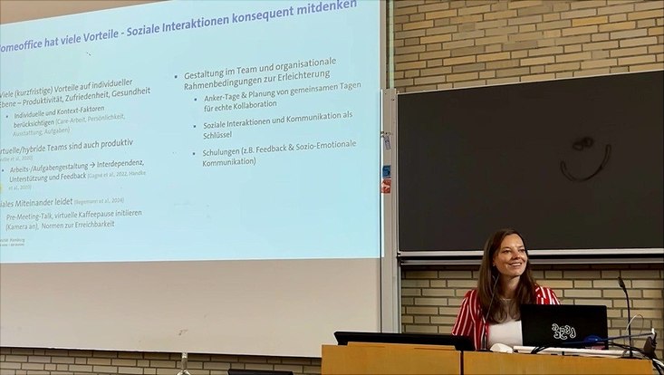 Frau steht hinter einen Stehpult und hält einen Vortrag